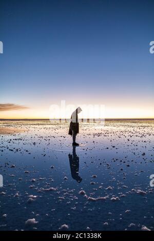 Uomo che sta in piedi sulla sua propria riflessione a Salt Flats in bolivia Foto Stock