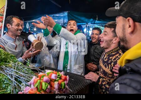 Bancarelle di cibo all'aperto di strada che cucinano e servono cibo nella piazza principale di Djemaa El Fna a Marrakech, Marocco, di notte Foto Stock