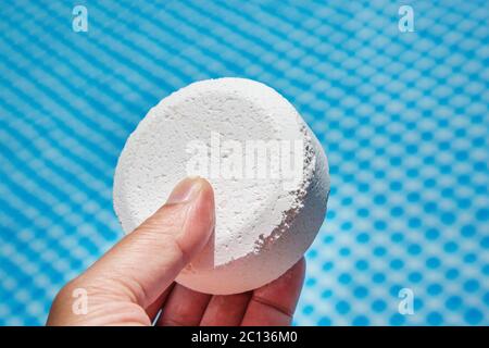 Mano azienda pellet di cloro con piscina gonfiabile su sfondo Foto Stock