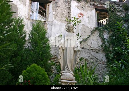 Una statua di Santa Maria ancora in piedi nel cortile di un edificio distrutto in Italia Foto Stock