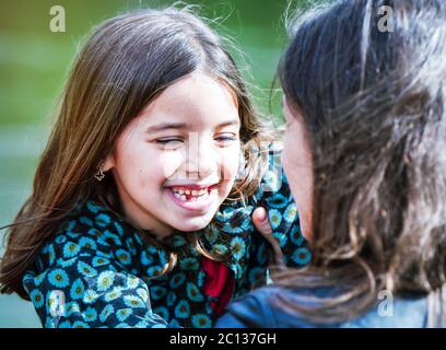 felice bambina che guarda la madre Foto Stock