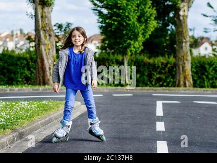 bambina che fa rollerblade in strada Foto Stock