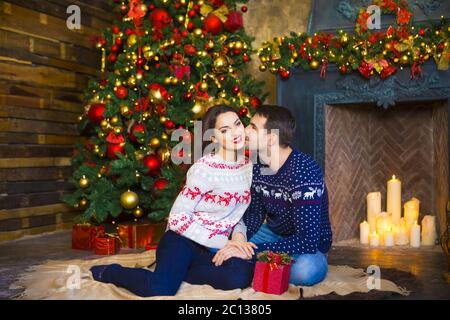 Giovane coppia vicino camino per festeggiare Natale Foto Stock