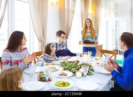 Amici seduti intorno a un tavolo e gustando insieme la cena di Natale Foto Stock