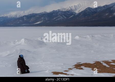 Donna meditando sulla spiaggia innevata del lago Baikal vicino a Santo naso penisola. Foto Stock