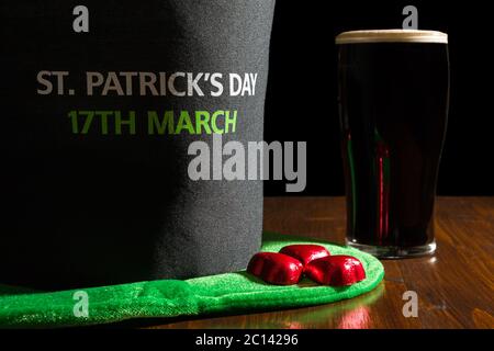 Primo piano di St Patrick giornata con una pinta di birra scura e hat su una tavola Foto Stock