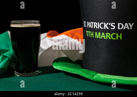 Primo piano di St Patrick giornata con una pinta di birra nera, cappello e bandiera irlandese Foto Stock