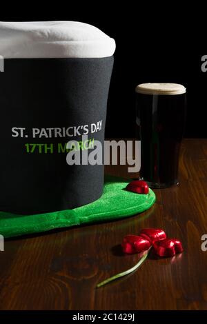 St Patrick giornata con una pinta di birra nera, cappello e shamrock su una tavola Foto Stock