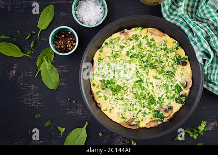 Spinaci e frittata di funghi. Frittata composta da uova, funghi e spinaci. Cucina italiana. Vista dall'alto, disposizione piatta, spazio per la copia Foto Stock