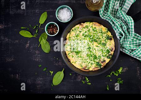 Spinaci e frittata di funghi. Frittata composta da uova, funghi e spinaci. Cucina italiana. Vista dall'alto, disposizione piatta, spazio per la copia Foto Stock