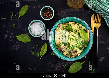 Spinaci e frittata di funghi. Frittata composta da uova, funghi e spinaci. Cucina italiana. Vista dall'alto, disposizione piatta, spazio per la copia Foto Stock