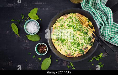 Spinaci e frittata di funghi. Frittata composta da uova, funghi e spinaci. Cucina italiana. Vista dall'alto, disposizione piatta, spazio per la copia Foto Stock