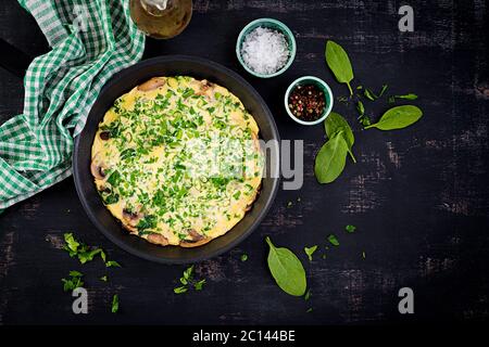 Spinaci e frittata di funghi. Frittata composta da uova, funghi e spinaci. Cucina italiana. Vista dall'alto, disposizione piatta, spazio per la copia Foto Stock