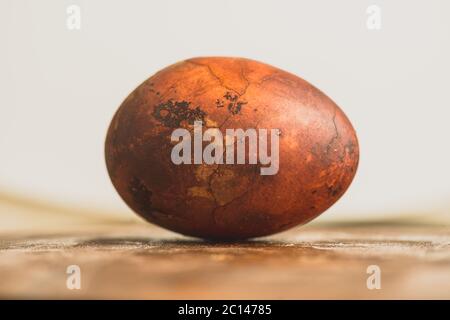 Uovo di Pasqua su sfondo di legno. Verniciato marrone con macchie e crepe. Primo piano di una macro Foto Stock