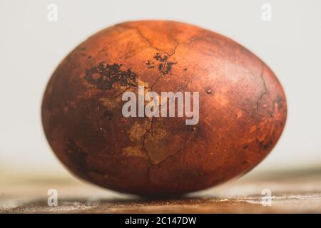 Uovo di Pasqua su sfondo di legno. Verniciato marrone con macchie e crepe. Primo piano di una macro Foto Stock