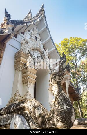 Phayao, Thailandia - 8 dicembre 2019: Chiesa tailandese bianca con serpente o Naga su sfondo foresta con luce naturale in vista ritratto Foto Stock