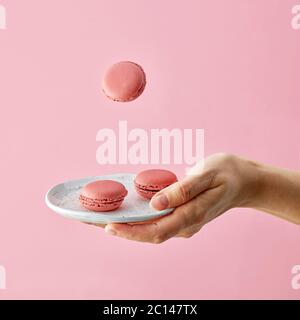 piatto di macaroni in mano umana isolato su sfondo rosa Foto Stock