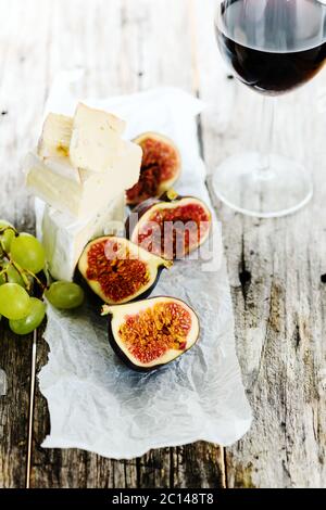 Uva, formaggio e fichi con un bicchiere di vino rosso Foto Stock