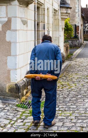 Vecchio francese che cammina a casa tenendo dietro la schiena un pane - Francia. Foto Stock