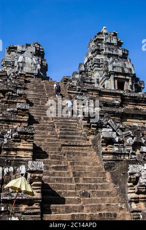 Due turisti arrampicandosi sui gradini ripidi fino alla cima dell'antico tempio Khmer Hindu a Ta Keo, Angkor, Cambogia. Costruito nel 985, la ripida scalinata è de Foto Stock