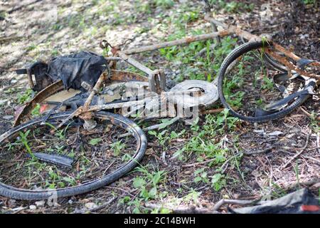 Vecchia bicicletta scartata arrugginita giacente su terra malforma e rotta Foto Stock