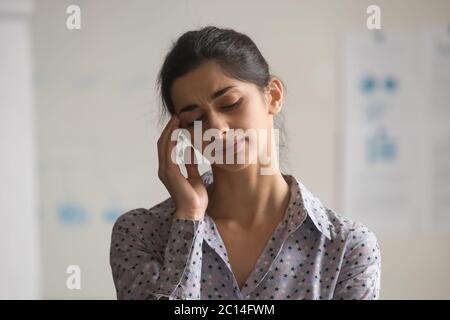 Infelice donna d'affari indiana che tocca templi, che soffrono di mal di testa Foto Stock