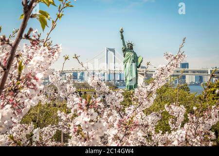 Questa replica della Statua della libertà si trova a Daiba, Tokyo. È stato girato durante la stagione dei fiori di ciliegio. Foto Stock