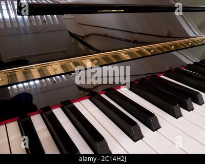 Particolare della tastiera di un pianoforte con tasti bianchi e neri e lucido coperchio riflettente Foto Stock