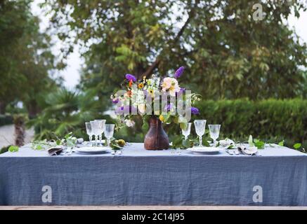 Mazzo di fiori rosa, viola e gialli su un tavolo per cena Foto Stock