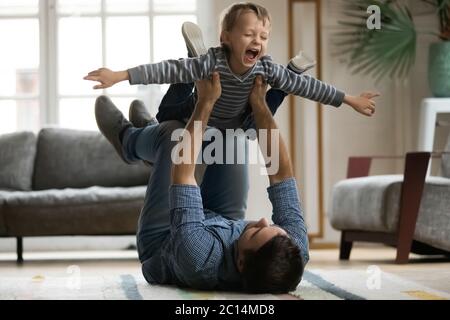 Ridendo ragazzino che finge di volare, giocando con felice padre Foto Stock