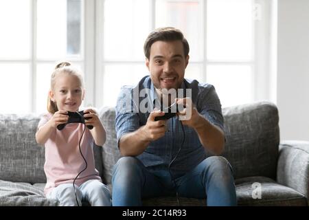 Felice padre e adorabile figlia che gioca a video gioco, tenendo gamepad Foto Stock