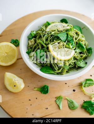 Spinaci grezzi di zucchine di spaghetti con salsa all'avocado e limone in piatto bianco. Su sfondo di legno. Gourmet di cucina italiana. Vista dall'alto Foto Stock