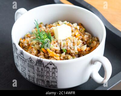 Grano saraceno con verdure in una ciotola bianca. Guarnito con un rametto di prezzemolo. Servendo porridge. Foto Stock