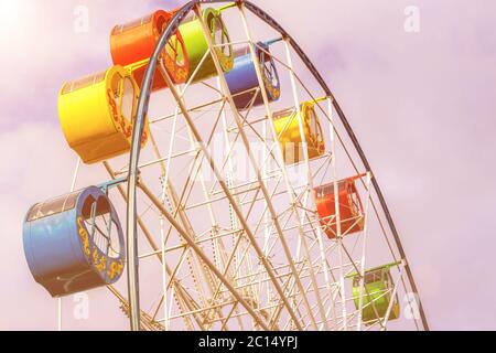 Ruota panoramica con cabine multicolore contro il cielo con nuvole nel parco in una soleggiata giornata primaverile. Foto Stock