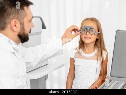 Medico oftalmologo che tiene speciali attrezzature oculari per esaminare gli occhi della ragazza in clinica Foto Stock