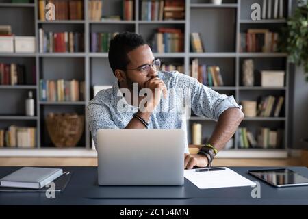 Uomo d'affari africano seduto sul posto di lavoro pensando alla soluzione del problema Foto Stock