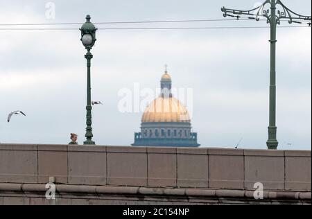 San Pietroburgo, Russia – 6 giugno 2020: Passeggiata di una giovane donna sul Ponte della Trinità. Sullo sfondo si trova la cupola della Cattedrale di Sant'Isacco Foto Stock