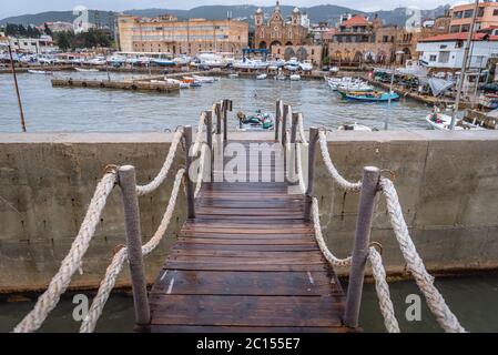 Ponte alle mura del mare nel porto della città di Batroun nel nord del Libano e una delle città più antiche del mondo, vista con la cattedrale di Santo Stefano sullo sfondo Foto Stock