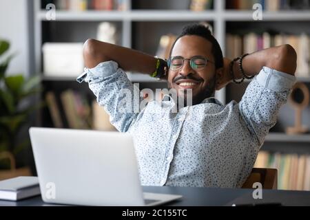 Il ragazzo africano messo le mani dietro la testa prende la pausa guardando il film Foto Stock