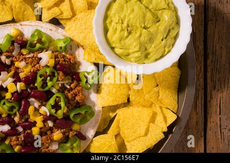 Tortilla messicana con carne, fagioli rossi, peperoncino jalapeno, nachos patatine e salsa guacamole Foto Stock