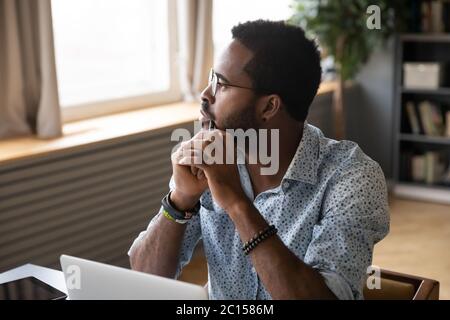 Ragazzo seduto al tavolo che meditando sul problema guardando la distanza Foto Stock