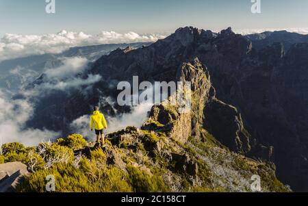 L'uomo si erge da solo sulla vetta della roccia. Bel momento il miracolo della natura. Nebbia colorata in valle. Uomo escursione. Trekking da Pico do Arieiro a Pico Foto Stock