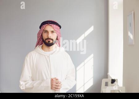 Uomo d'affari arabo sorridente ritratto su uno sfondo grigio Foto Stock