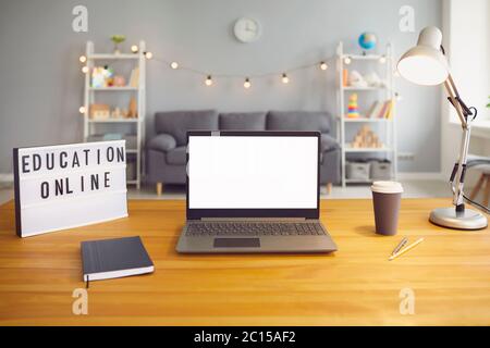 Segno di formazione online e computer portatile con schermo vuoto in piedi su tavolo di legno in soggiorno, mockup per il design Foto Stock
