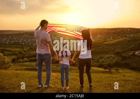 Vista posteriore Famiglia con umidità americana in natura al tramonto. FESTA DELL'indipendenza DEGLI STATI UNITI 4 luglio Foto Stock