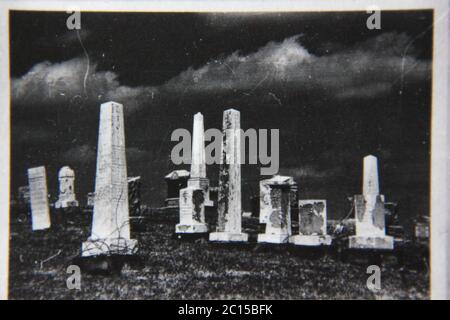 Fine anni '70 vintage in bianco e nero fotografia estrema di lapidi in piedi in un vecchio cimitero. Foto Stock