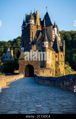 Ponte e Burg Eltz circondato da alberi verdi in montagna in un giorno di primavera tedesco. Foto Stock