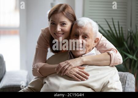 Testa ritratto girato sorridendo figlia abbracciando padre più anziano dalla parte posteriore Foto Stock