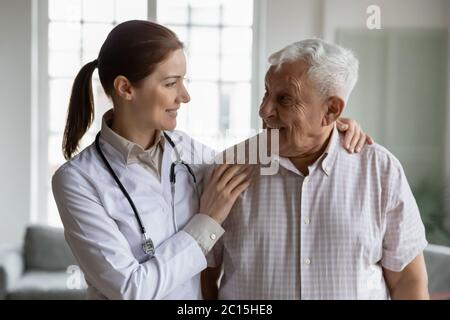 Testa ritratto sorriso femmina medico abbracciando l'uomo più anziano Foto Stock