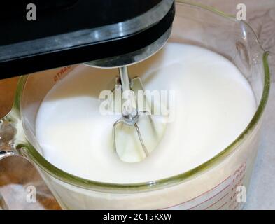 Primo piano foto di un mixer che monta gli ingredienti in un recipiente di vetro. Foto Stock
